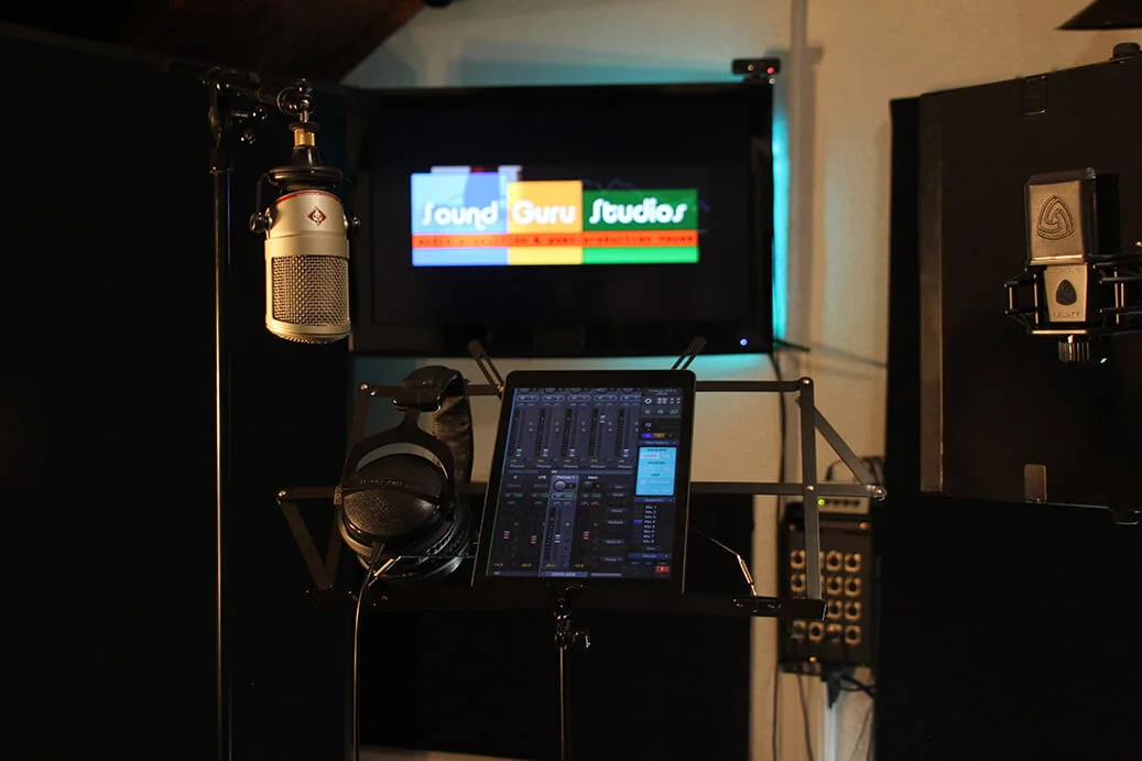 Sound recording room with two studio microphones, headphones and tablet control surface.